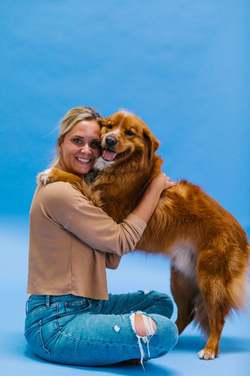 Una mujer abrazando a un perro dorado feliz